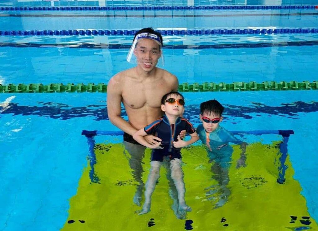 A swim instructor in a pool with two young boys